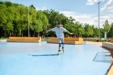 Full-length portrait of a smiling cheerful boy in the knee pads roller-skating on the rink