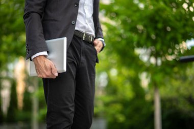 İşe koyulalım. Siyah takım elbiseli bir adam elinde tabletle yürüyor.