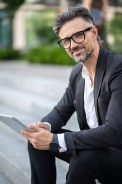 Randevu. Sakallı işadamı elinde bir aletle birini bekliyor.