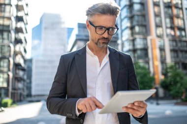 Dışarıda çalış. Elinde tabletle meşgul görünen bir iş adamı.