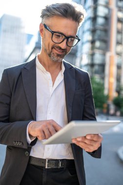 Dışarıda çalış. Elinde tabletle meşgul görünen bir iş adamı.