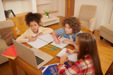 Online studying. A group of kids studying remotely together and writing something down