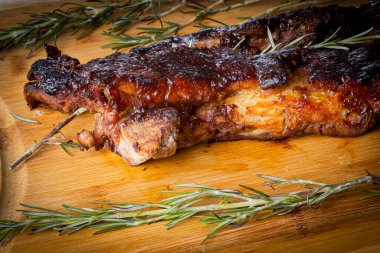 Ahşap bir tahtanın üzerinde Rosemary barbekü soslu domuz pirzolası. Perspektif görünümü.