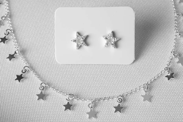 Elegant sterling silver earring jewelry with gemstones and a sterling silver necklace with star accents. White background.