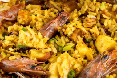 Classic Spanish dish. Spanish paella with prawns, octopus, squid, mussels, onion, tomato, garlic, olive oil and lemon. Assembled on white plate. Close view.