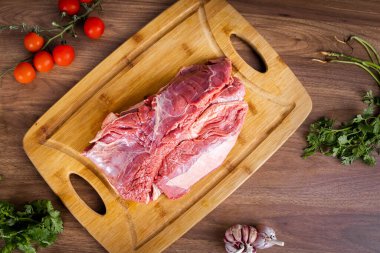 FLANK STEAK beef BBQ food. Raw meat covered with fat on a wooden board on a wooden background. Seasoned with cilantro, garlic and tomatoes.