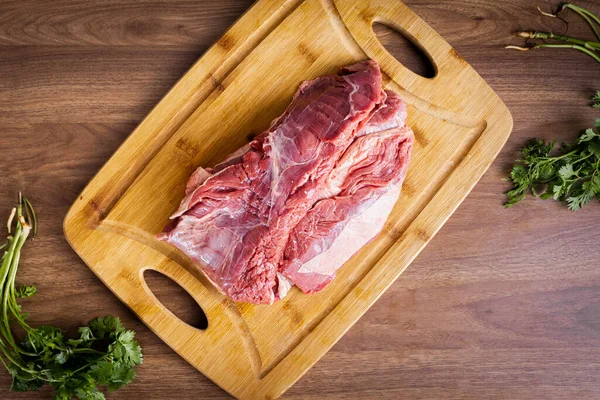 FLANK STEAK beef BBQ food. Raw meat covered with fat on a wooden board on a wooden background. Seasoned with coriander.