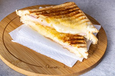 Grilled ham and cheese. Sandwich with cheese and ham on the grill. Served on a wooden board.