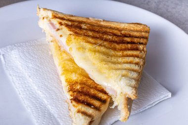 Grilled ham and cheese. Sandwich with cheese and ham on the grill. Served cut in half.