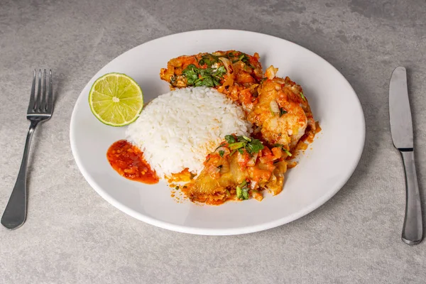 stock image Delicious Brazilian fish moqueca with tomato, onion, olive oil, coriander and orocum seed. Served on a white porcelain plate with rice.