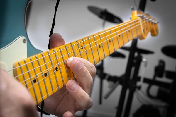Blue electric guitar in musical solo, showing in detail the string being lifted.