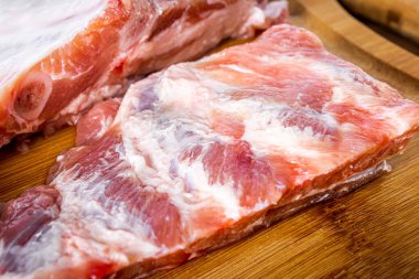 Tahta tahtada kesilmiş çiğ domuz kaburgası ve ahşap masa. Yakın görünüm.