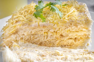 Tipik bir Brezilya yemeği olan dondurulmuş baharatlı tavuk turtası kesiyorum. Beyaz tabakta, gri ahşap arka planda. Tahta kaşık, çatal bıçak takımı ve kaju suyunun yanında. Yakın görünüm.