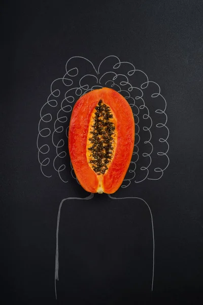 a papaya cut in half on a solid black background and the silhouette of a woman with curly hair, concept of female health, healthy vagina, no people