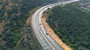 İnsansız hava araçları tepedeki yeşil ağaçlar ve sabah güneşinin etrafından geçiyor. İnsanlar yok.