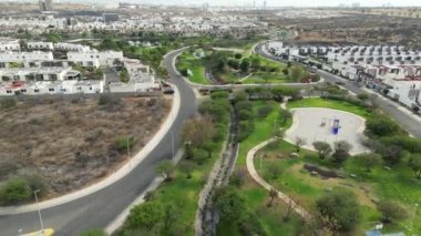 Öğleden sonra gölleri ve yeşil alanları olan bir şehir parkında İHA turu, etrafında evler, dron manzaralı