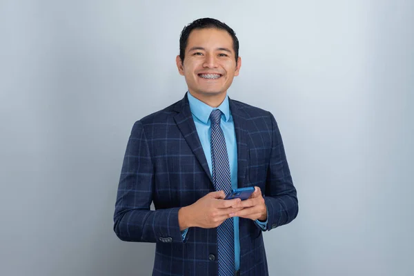 若いヒスパニック系の男は 起業家の服や青いネクタイで仕事のために身に着けています 笑顔ながら 電話のテキスト — ストック写真