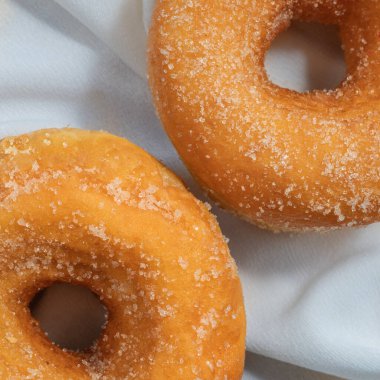 Beyaz masa örtüsüne iki vanilyalı şekerli çörek yakın plan, insan yok.