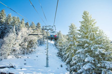People on the chairlift enjoying the landscape and the snow doing outdoor sports in winter, skiing in a sunny ski resort