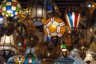 Fas 'ta gerçek bir çarşıda tavandan sarkan renkli cam fenerler. Fenerler çeşitli şekil ve boyutlarda ve aydınlatılarak sıcak ve davetkar bir atmosfer yaratıyorlar..