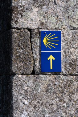 Camino de Santiago 'daki hacılar için tabelalar. Mavi arka planda tipik bir sarı ok ve kabuk yolu gösterir.