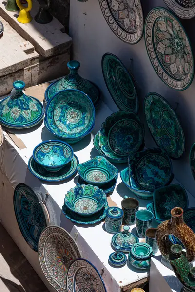 Canlı mavi ve yeşil desenli geleneksel Fas çömlekleri, bir pazar tezgahında sergilenerek, yerel zanaatkarlığa bir bakış sunuyor