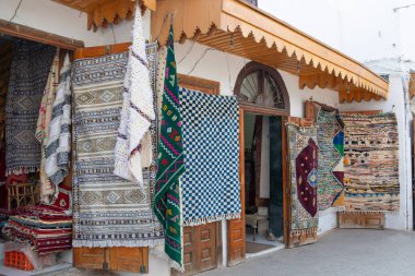 Çarşıda renkli berber halılar sergileyen geleneksel Fas dükkânı.