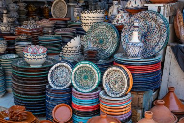 Elle boyanmış tabaklar, kaseler ve etiketler Fas işçiliğinin büyüleyici bir görüntüsünü oluşturuyor.