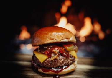 Cheeseburger on a wooden table in front of a fireplace.