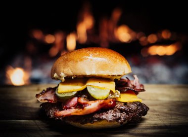 Smashed Cheeseburger on a wooden table in front of a fireplace.