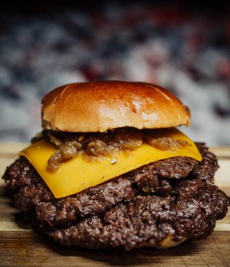 Smashed Cheeseburger on a wooden table in front of a fireplace.