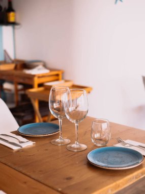 Güzel bir sahil restoranında tabak, peçete ve bardaklı masa ve sandalyeler.