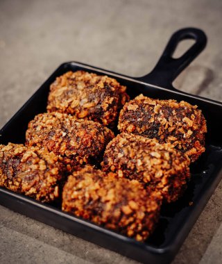 Kızarmış tavuk köfteleri, siyah tabakta mermer bir arka planda.