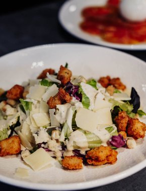 Beyaz tabakta kızarmış ekmek ve peynirli Sezar salatası.