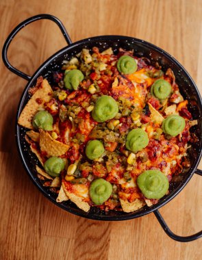 Bir tabak nachos, et, peynir ve guacamole.