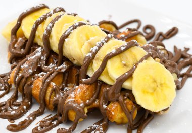 Muz ve çikolatalı waffle bir restoranda beyaz bir tabakta.