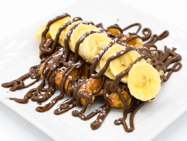 Muz ve çikolatalı waffle bir restoranda beyaz bir tabakta.