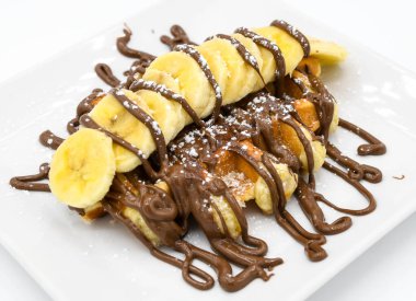 Muz ve çikolatalı waffle bir restoranda beyaz bir tabakta.