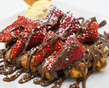 Çikolatalı waffle ve çilek yakın plan beyaz tabakta.