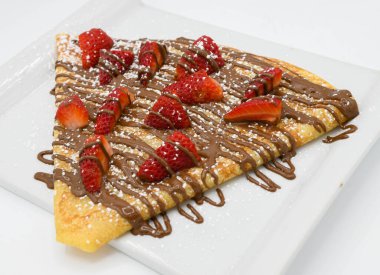 Çilekli krep ve beyaz tabakta çikolata..