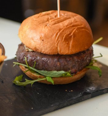 150 gram gourmet burger of premium beef with brioche bread and arugula clipart