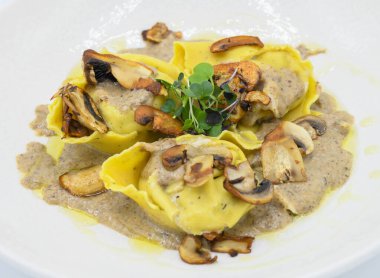 Restoranda beyaz bir tabakta mantar soslu Ravioli.