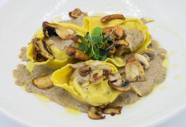 Restoranda beyaz bir tabakta mantar soslu Ravioli.