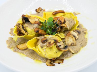 Restoranda beyaz bir tabakta mantar soslu Ravioli.