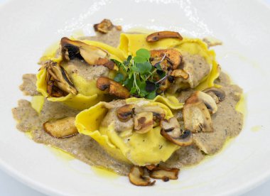 Restoranda beyaz bir tabakta mantar soslu Ravioli.