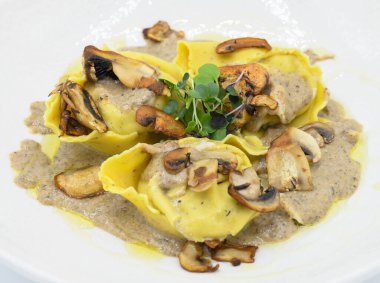 Restoranda beyaz bir tabakta mantar soslu Ravioli.