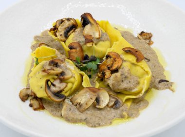 Restoranda beyaz bir tabakta mantar soslu Ravioli.