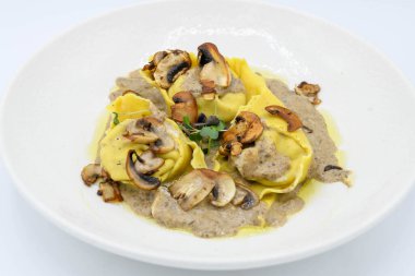 Restoranda beyaz bir tabakta mantar soslu Ravioli.