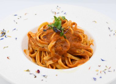 Noodles bolognese with tomato sauce on a white plate clipart