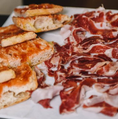 Beyaz bir tabakta dilimlenmiş jambon ve ekmek.